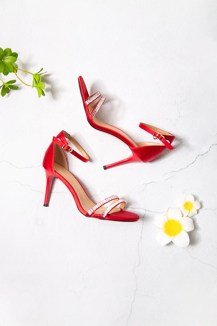 A pair of stylish red high heels paired with flowers on a light background.